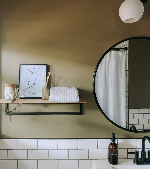 Stack of white waffle towels on a shelf next to a round mirror